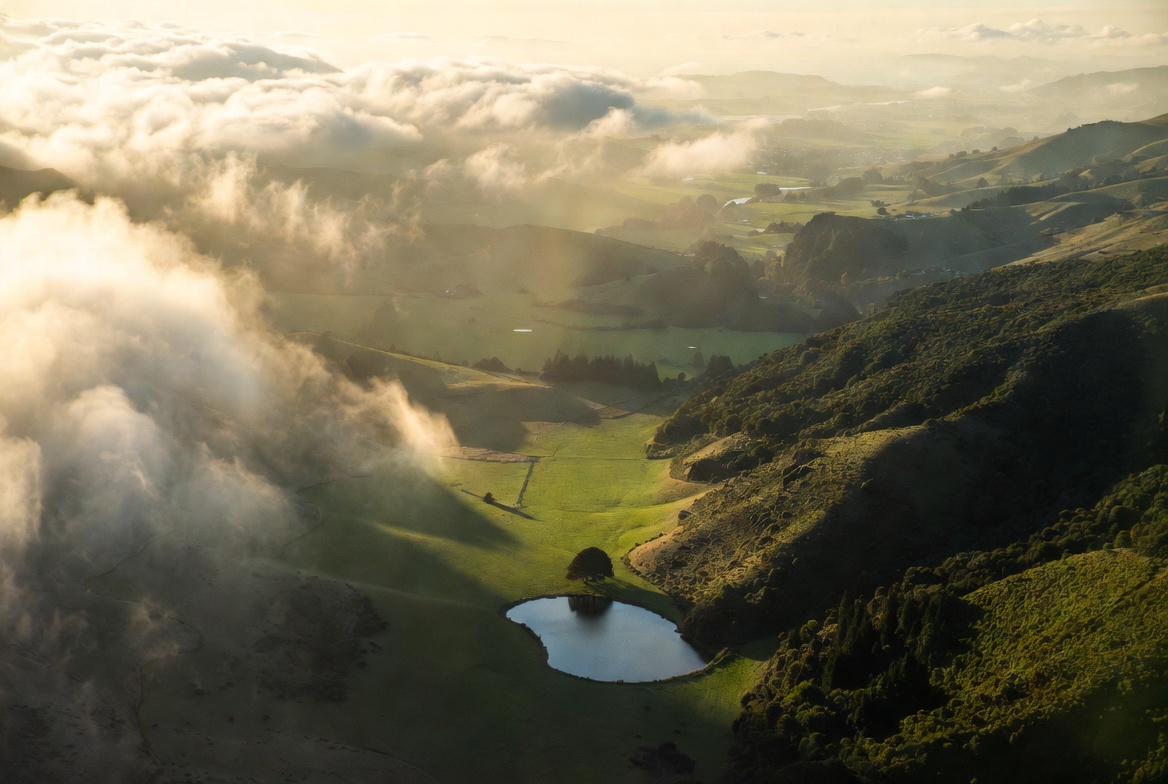 Aerial view of a green New Zealand valley seen through cloud